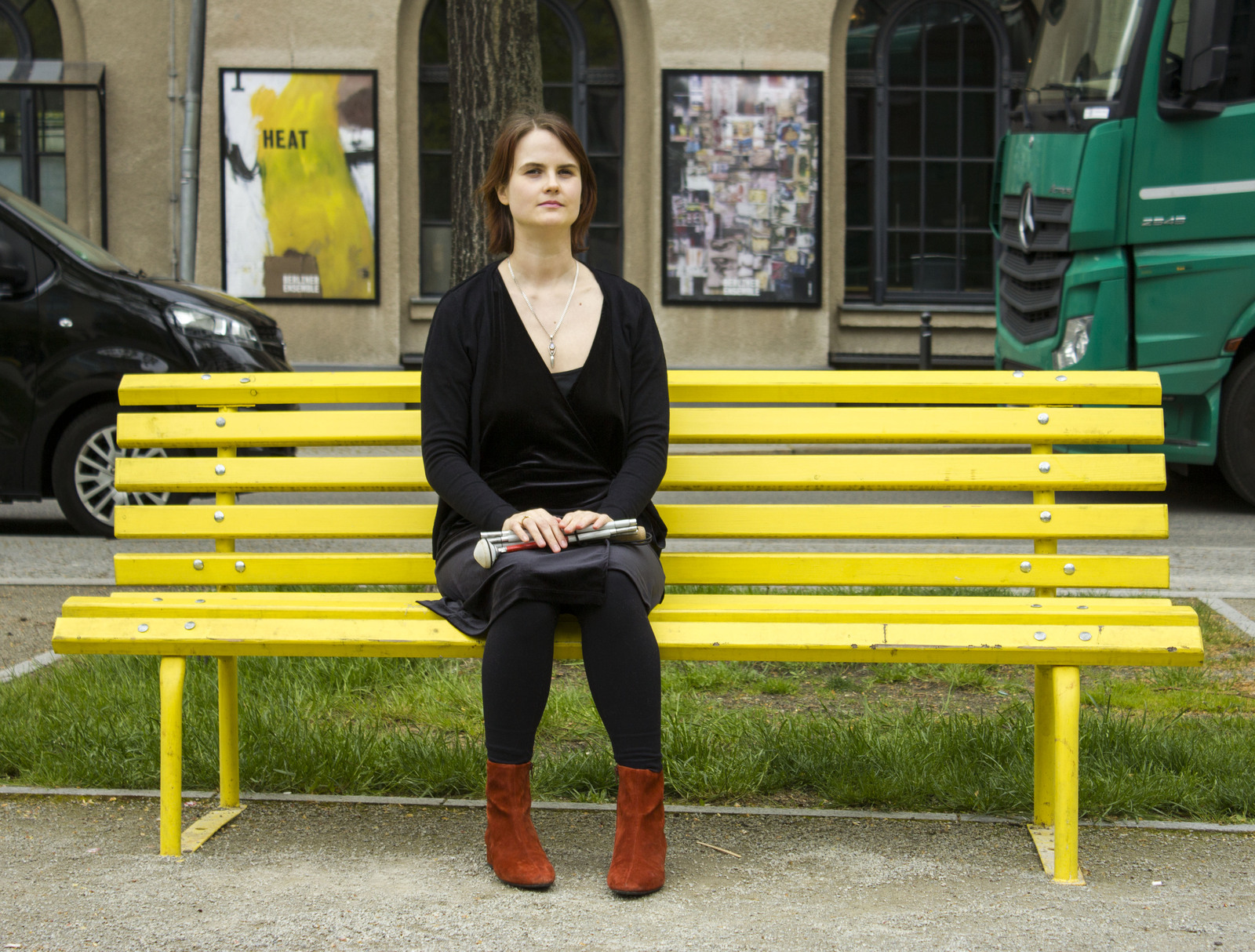 Lavinia sitzt auf einer gelben Bank vor dem Berliner Ensemble.
